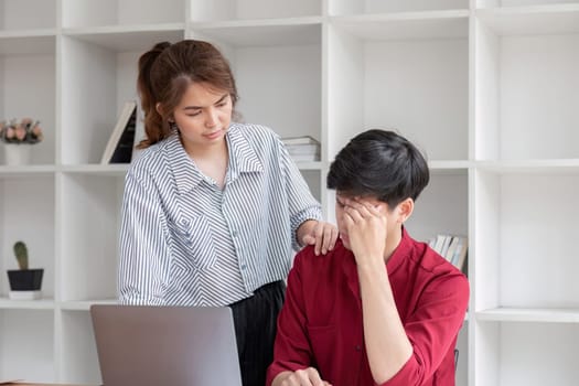 Two businessmen are stressed while explaining workflow on laptop to colleague..