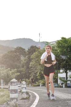 Young sporty woman jogging in the green park in the evening.