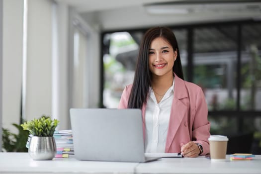 Businesswoman working with laptop computer while having a leisurely cup of coffee at the office in the morning..