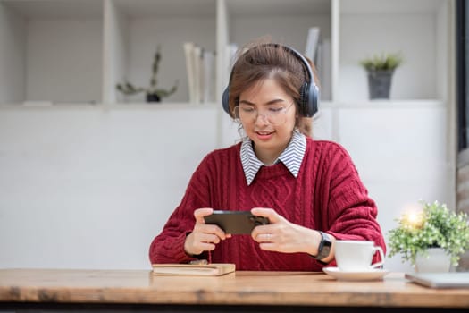 Excited Asian woman playing online game on her smartphone with live broadcasting on internet. cell telephone technology e-commerce concept.