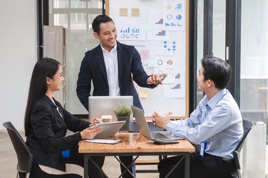 Professional businessman presenting to colleagues in conference room explaining growth chart.