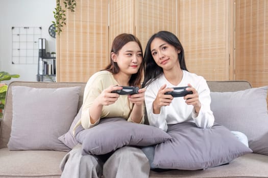 Young Asian couple playing video games at home in the living room having fun..