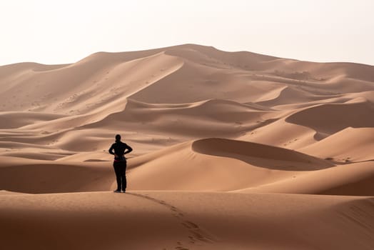 A person walking through the Erg Chebbi desert in the African Sahara, Morocco