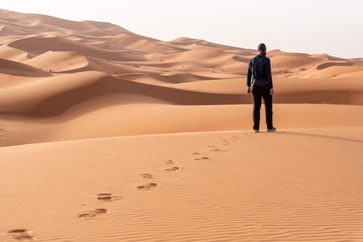 A person walking through the Erg Chebbi desert in the African Sahara, Morocco