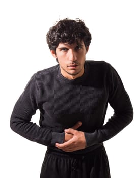 A young man is suffering from belly-ache, stomach ache, in a black sweater and black pants