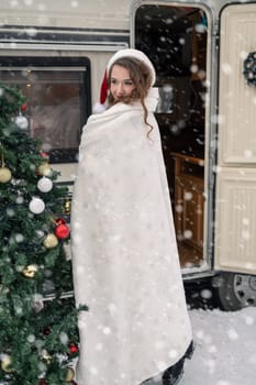 Young woman in santa costume decorates the Christmas tree at winter campsite getting ready for the new year. New year celebration concept