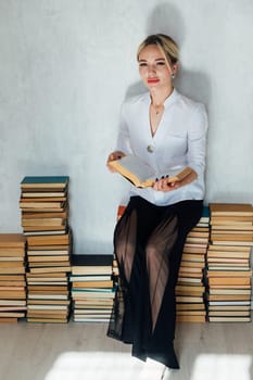 Woman sitting on stacks of books in library