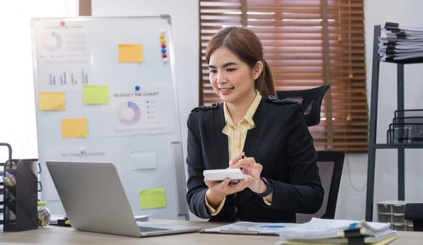 Businesswoman uses calculator to calculate finances, mathematics on table in office and business charts, tax, accounting, statistics and analytical research concept..