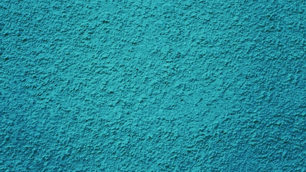 Rough texture of old plaster of an abandoned blue green wall.