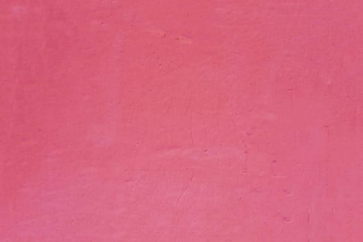 A fragment of an old, shabby concrete wall of red, dark pink color.