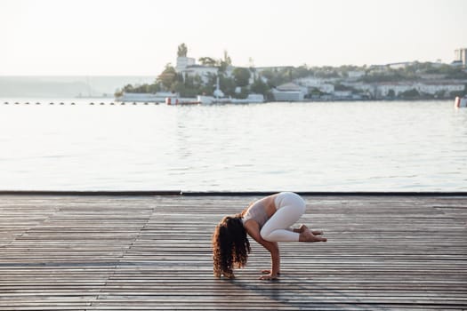 Full length portrait of a middle aged woman doing yoga or pilates on a mat outside in a park.