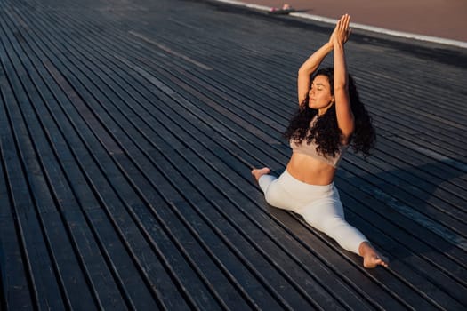 Full length portrait of a middle aged woman doing yoga or pilates on a mat outside in a park.