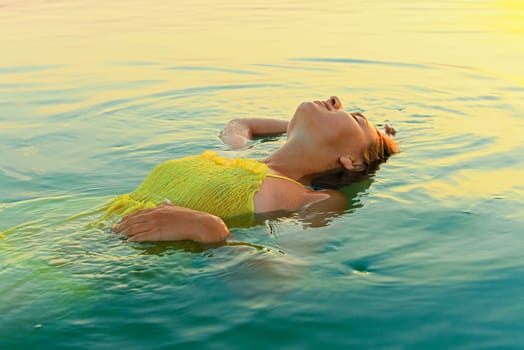 young woman immersed in water, illuminated by the rising sun