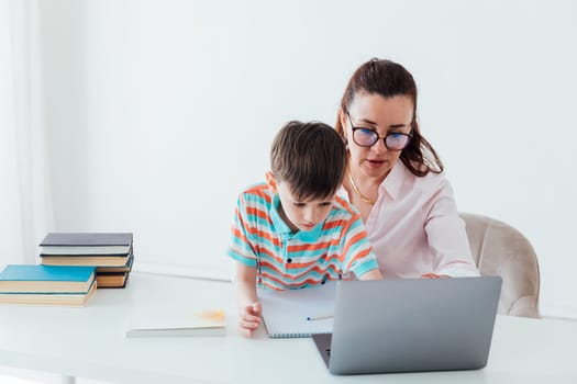 Woman with boy watching online laptop at table at school