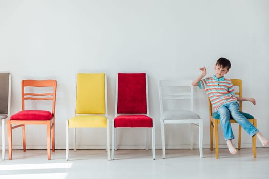 A 7-year-old boy and many different chairs in the interior of a white room