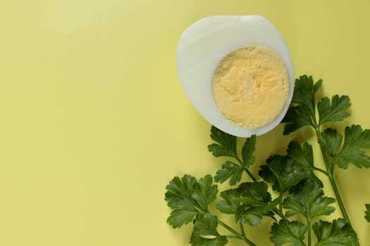 Green parsley and a boiled chicken egg on a yellow background. High quality photo