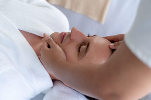 Caucasian man enjoying relaxing anti-stress head massage and pampering facial beauty skin recreation leisure in dayspa modern light ambient at luxury resort or hotel spa salon. Quiescent