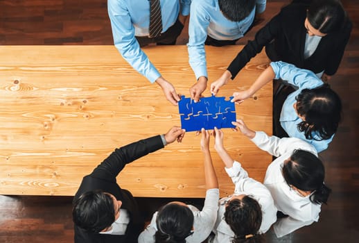 Multiethnic business people holding jigsaw pieces and merge them together as effective solution solving teamwork, shared vision and common goal combining diverse talent. Panorama top view. Meticulous