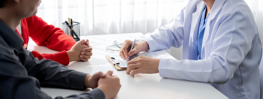 Couple attend fertility consultation with gynecologist at hospital as part family planning care for pregnancy. Loving husband and wife support each other through the doctor appointment. Panorama Rigid