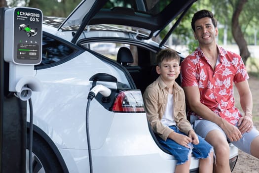 Family road trip vacation with electric vehicle, father and son recharge EV car with green and clean energy. Nature and travel with eco-friendly car for sustainable environment. Perpetual