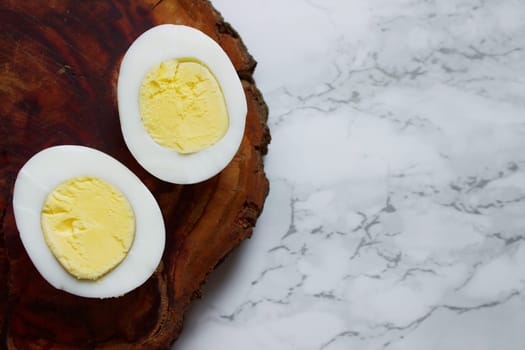 Boiled chicken egg on a wooden board on a marble background. High quality photo