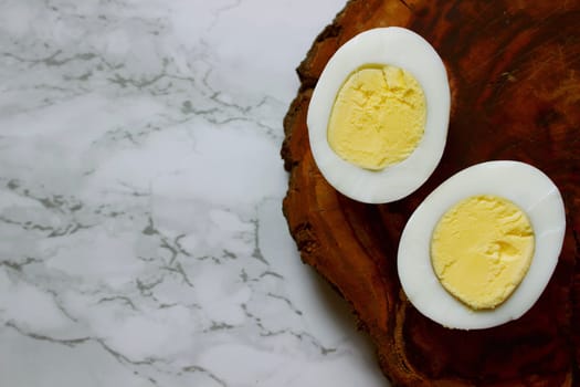 Boiled chicken egg on a wooden board on a marble background. High quality photo