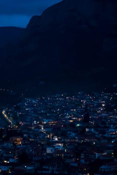 View of a small village among the mountains with street lights illuminated by lanterns late at night, in the dark, a scenic beautiful cityscape.