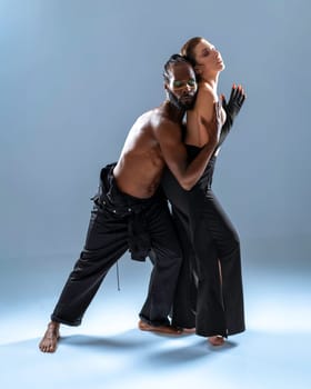 Black gay man hugging woman coming up from behind. Two person dancing on blue background. Male and female dancers. African-American and Brazilian man and woman hug each other while dance