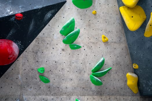 Colored bright painted climbing wall for training at bouldering gym. Multi-colored climbs walls with no people on it. Climb wall with different colorful grips in contemporary gym closeup