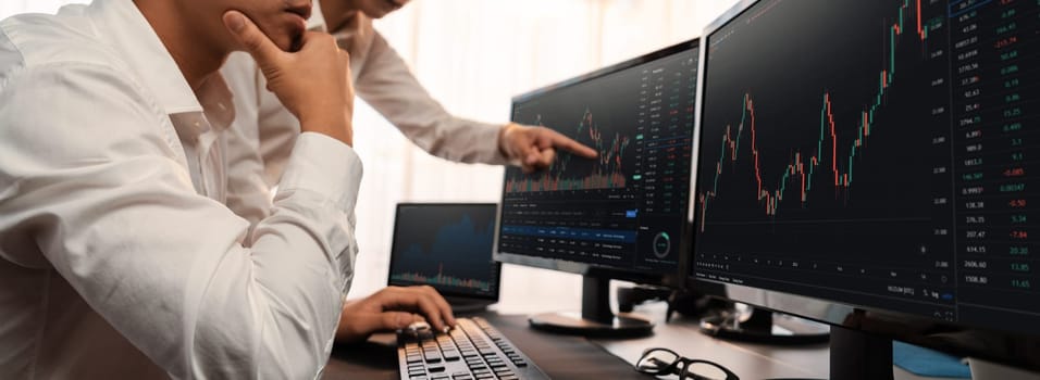 Group of traders discussing on office desk, monitoring stock market on monitor at office workplace. Businessman and broker analyzing stock graph together at stock trading company. Trailblazing