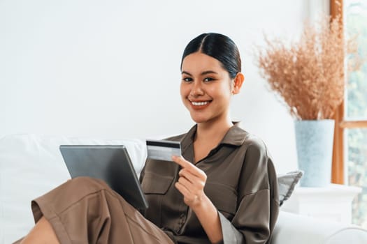 Young happy Asian woman buy product by online shopping at home while ordering items from the internet with credit card online payment protected by uttermost cyber security from online store platform