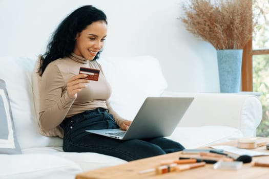 Young happy woman buy product by online shopping at home while ordering items from the internet with credit card online payment system protected by crucial cyber security from online store platform