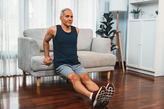 Athletic and active senior man using furniture for effective targeting muscle with push up at home exercise as concept of healthy fit body lifestyle after retirement. Clout