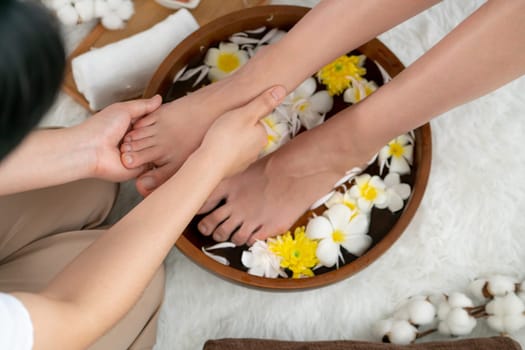 Woman indulges in blissful foot massage at luxurious spa salon while masseur give reflexology therapy in gentle day light ambiance resort or hotel foot spa. Quiescent