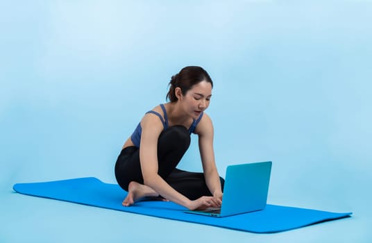 Young asian woman in sportswear stretching before fitness exercise following instruction from online video. Body workout with healthy athletic woman warming up on isolated background. Vigorous