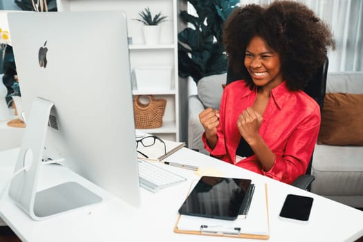 African woman blogger exited with happy face, looking on screen with valued stock market achievement at high profit. Concept of exchange investment online in trading application on pc. Tastemaker.