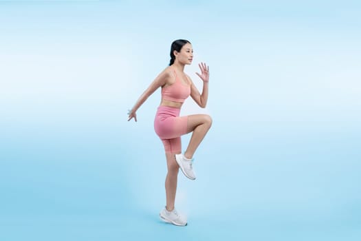 Side view young athletic asian woman on running posture in studio shot on isolated background. Pursuit of healthy fit body physique and cardio workout exercise lifestyle concept. Vigorous