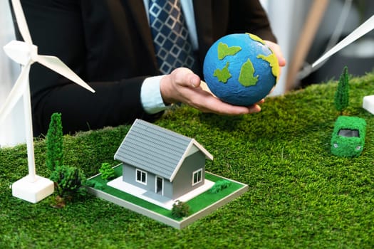 Eco business and save Earth concept shown by businessman or CEO holding paper globe in office with eco friendly mockup to promote CO2 and carbon footprint reduction for greener future. Quaint