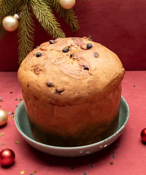 Christmas Panettone Italian Cake On Red Background with Christmas Toys, Decorations. Fruitcake Originally From Italy, Sweet bread. Milan Baked Dessert. Vertical plane. High quality photo
