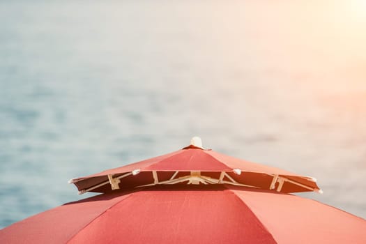 Red Beach Umbrella on the Background of the Blue Sea Ocean. Beach Landscape. Summer travel and holidays concept