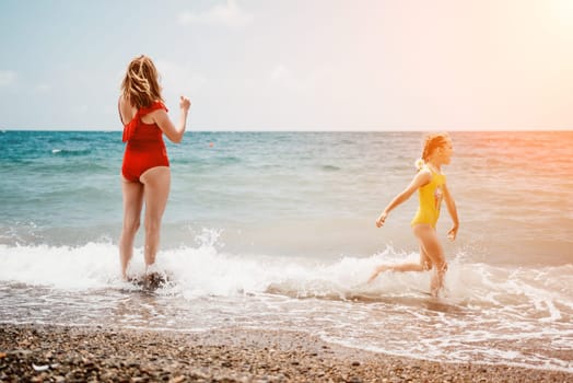 Happy loving family mother and daughter having fun together on the beach. Mum playing with her kid in holiday vacation next to the ocean - Family lifestyle and love concept.