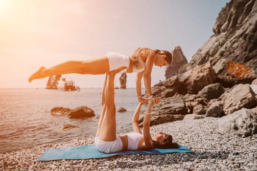 Woman sea yoga. Back view of free calm happy satisfied woman with long hair standing on top rock with yoga position against of sky by the sea. Healthy lifestyle outdoors in nature, fitness concept.