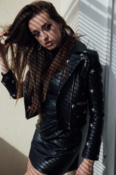a brunette in leather clothes stands in sunset light