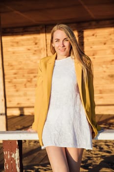 beautiful blonde woman in a light summer dress and yellow jacket