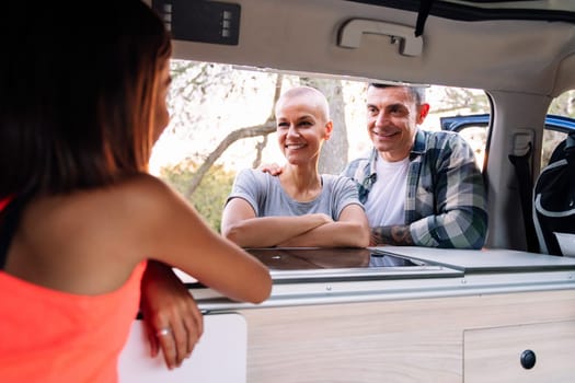 family relaxing happy and enjoying their camper van in the countryside, concept of adventure travel with children and active tourism in nature