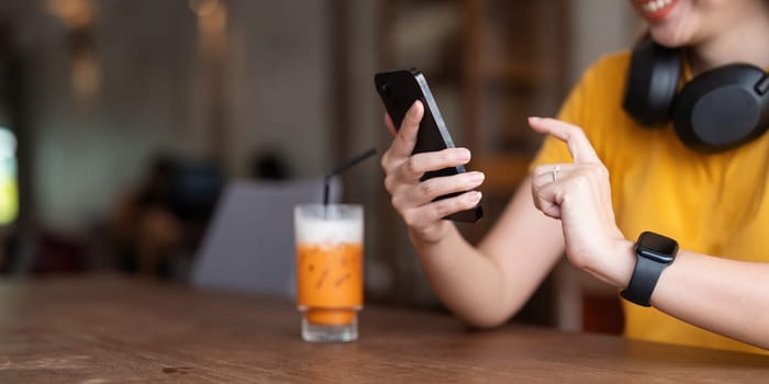 Young woman wearing headphones listening to music on her smartphone relax in cafe.