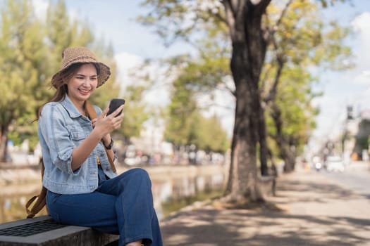 Young beautiful smiling asian woman tourist in city street using mobile phone check direction or use social media.