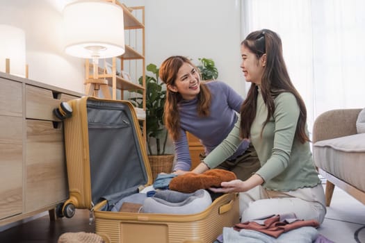 Young Asian woman packs clothes into a suitcase. Preparing for the summer vacation Two women are planning a trip and helping prepare their suitcases for a trip abroad..