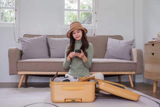 Attractive asian young woman packing a travel bag before going on holiday. Life style concept..