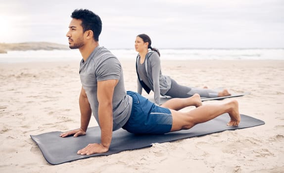 Exercise, yoga and wellness with a couple on the beach for a mental health or awareness workout in the morning. Fitness, pilates or mindfulness with a young man and woman by the ocean or sea for zen.